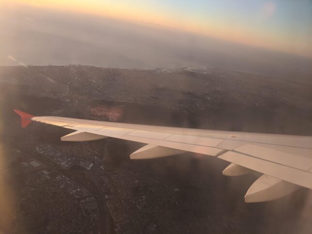 Pohled z okýnka letadla na křídlo a Barcelonu